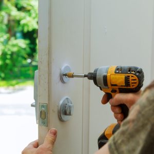 Installation locked interior door knobs, close-up woodworker hands install lock. installation of a lock at the door