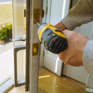 Worker installing lock in new house with using screwdriver